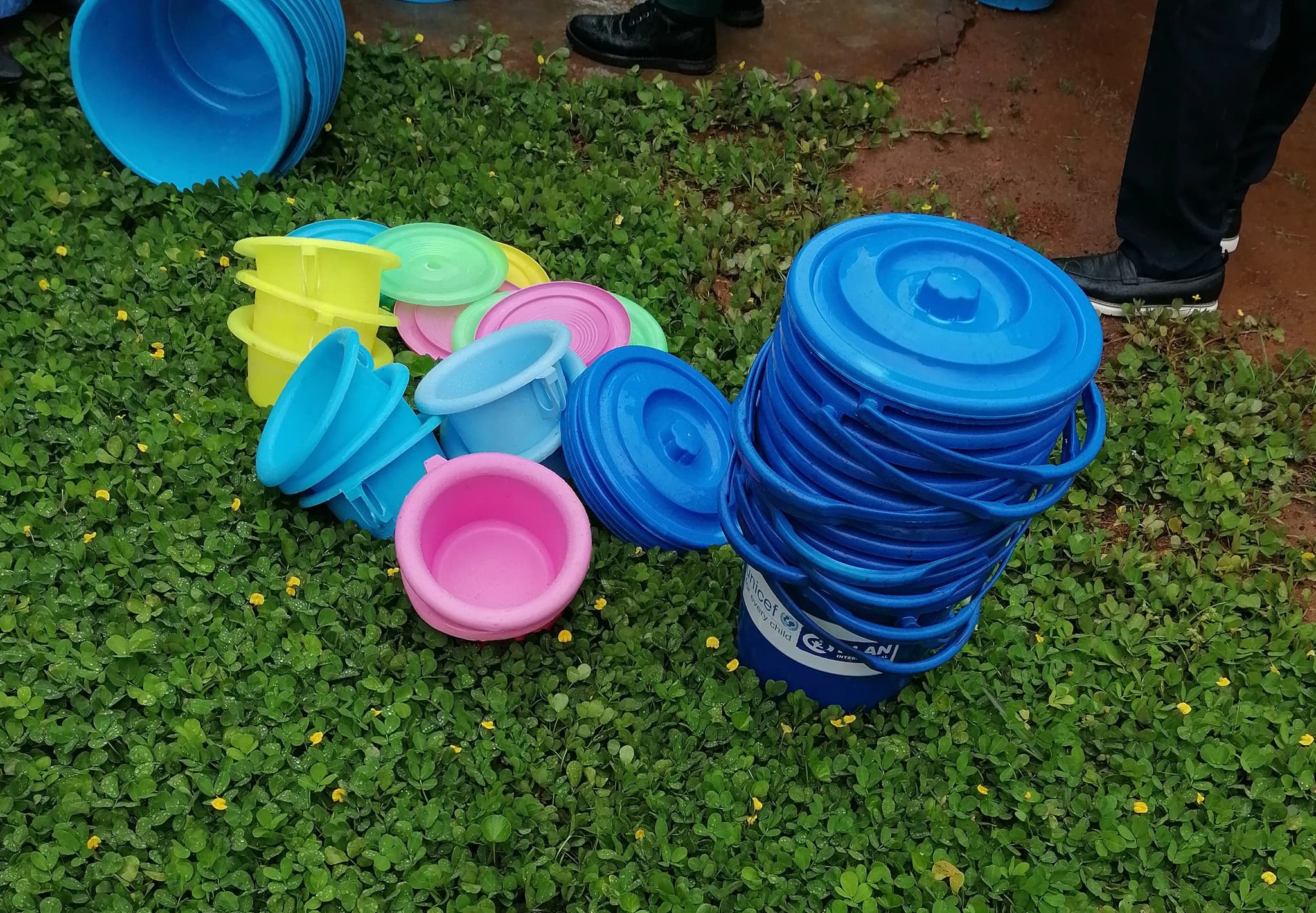 Seaux bleus et récipients ménagers colorés posés sur l’herbe